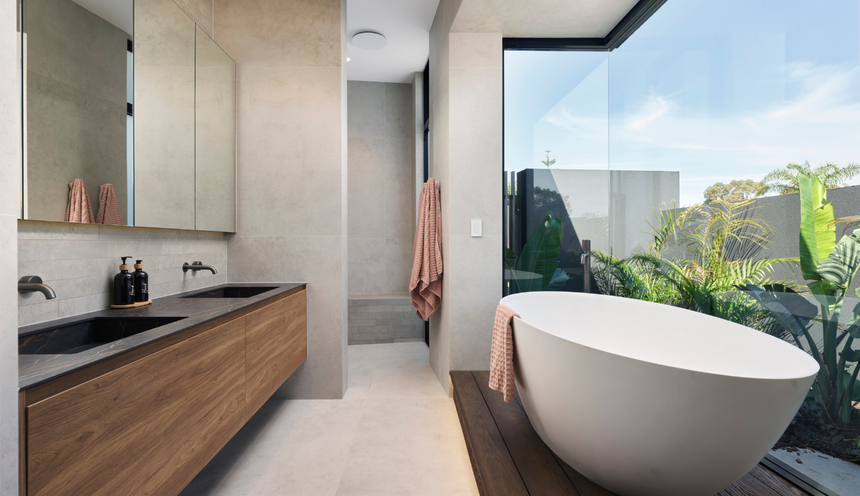 Luxury bathroom in a Marmion custom home featuring a freestanding bath, natural stone finishes and large windows.