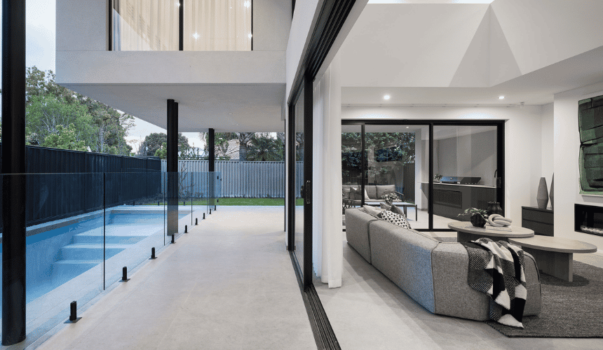 Outdoor swimming pool and alfresco area featuring expansive glazing and landscaped gardens at a custom home in Ardross.