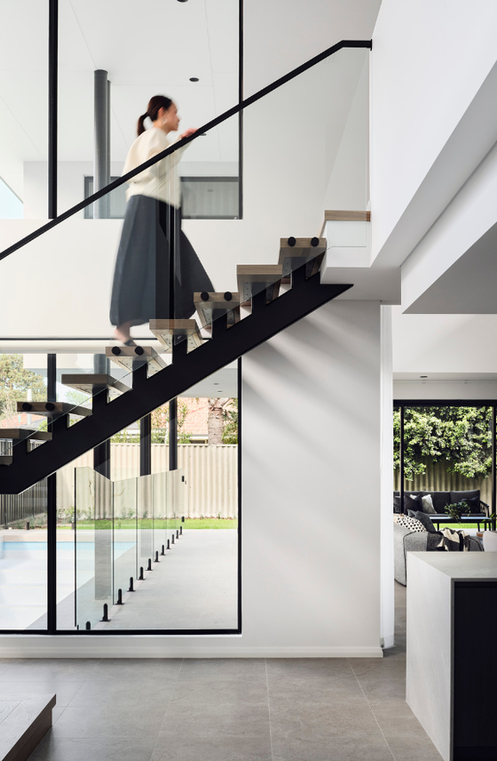 Floating timber staircase with glass balustrading and large windows in a contemporary Ardross custom home.