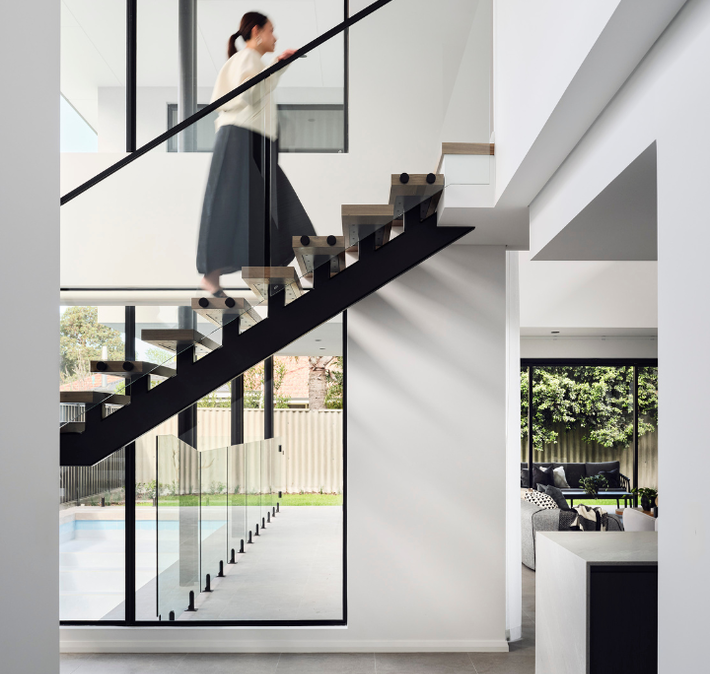 Floating timber staircase with glass balustrading and large windows in a contemporary Ardross custom home.