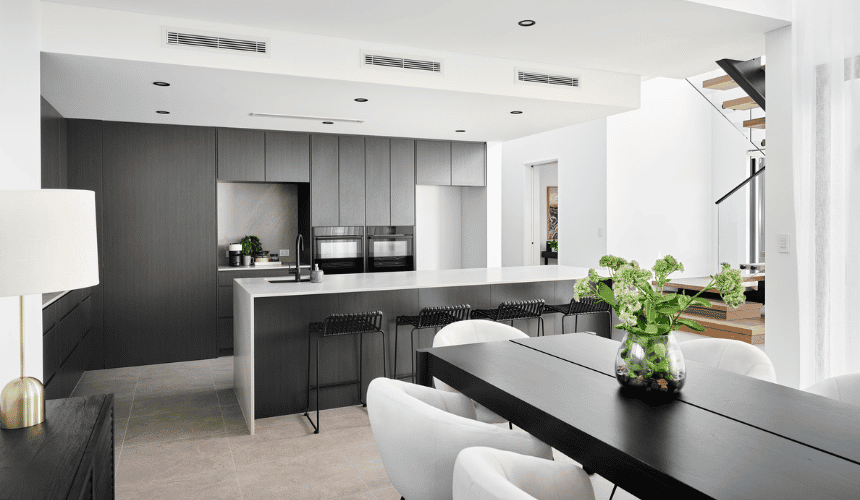 Modern kitchen in an Ardross custom home featuring dark cabinetry, stone island benchtop and open-plan living.