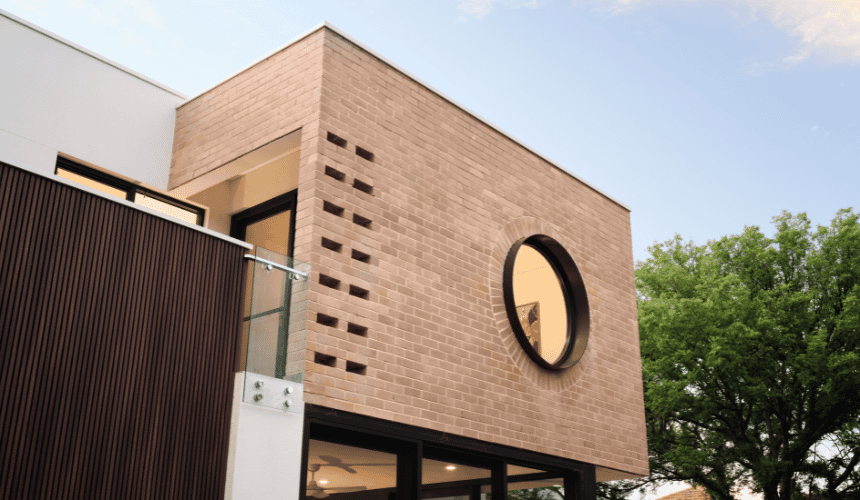 Close-up of a circular architectural window set within a textured brick facade at a custom home in Nedlands.