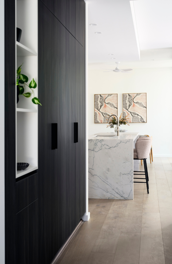 Light-filled entry hallway in a Nedlands custom home featuring white cabinetry, decorative artwork and timber flooring.