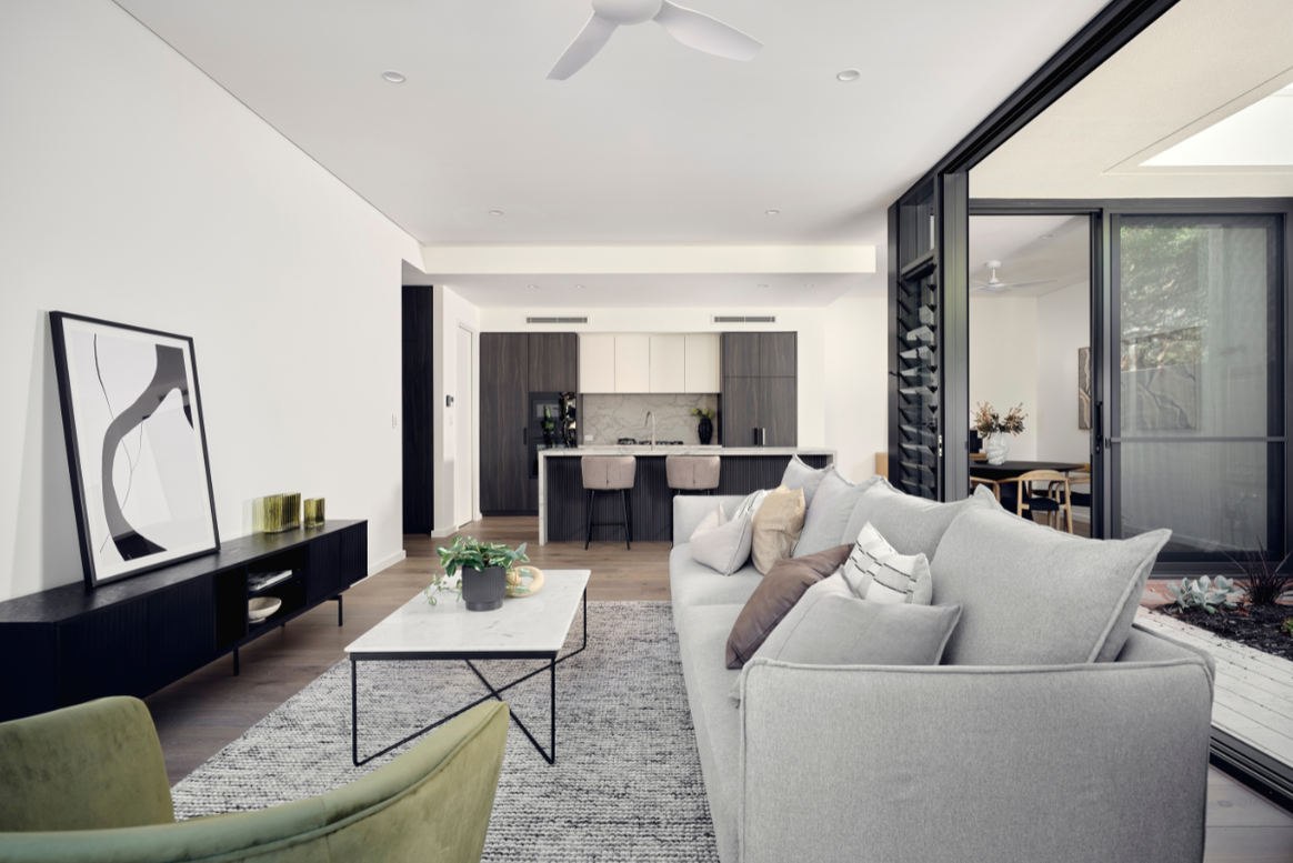Open-plan living and kitchen area in a Nedlands custom home featuring white cabinetry, timber flooring and contemporary furnishings.