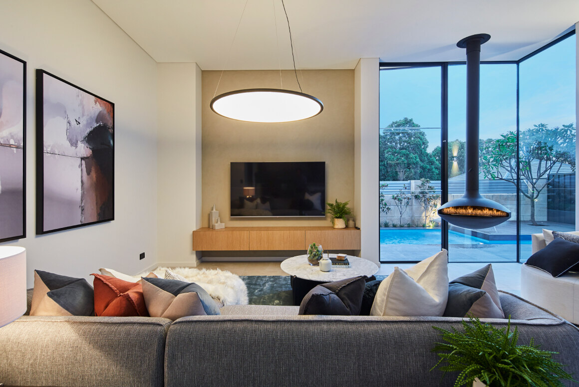 Modern living room inside a luxury custom built home with hanging fire place and throw pillows