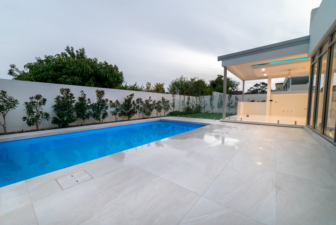 A luxury custom-built home showcasing a contemporary swimming pool and large full length windows