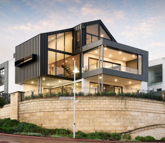 A custom modern home on a corner block towering over the street with interesting industrial elements by Trendsetter Homes.