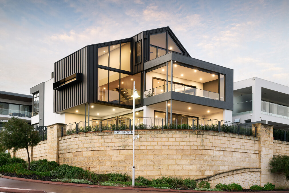 A custom modern home on a corner block towering over the street with interesting industrial elements by Trendsetter Homes.