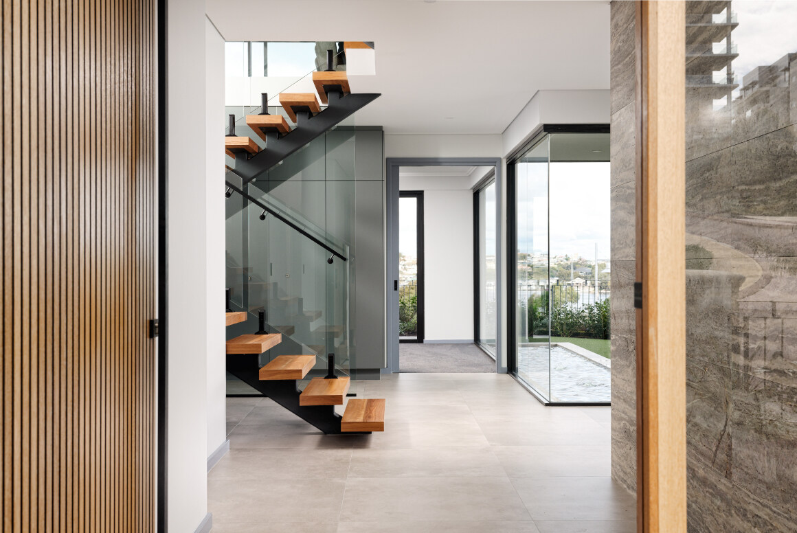 A modern wooden staircase going to the second floor of a white and wooden modern luxury custom built home