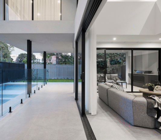Outdoor swimming pool and alfresco area featuring expansive glazing and landscaped gardens at a custom home in Ardross.