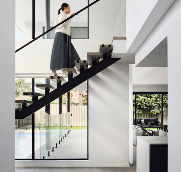 Floating timber staircase with glass balustrading and large windows in a contemporary Ardross custom home.